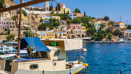 Symi town on Symi island with colorful neoclassical houses, boats in the foreground, Greece