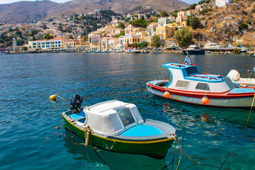 Symi town on Symi island with colorful neoclassical houses, boats in the foreground, Greece