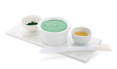 Bowl of spirulina facial mask, ingredients and spatula on white background