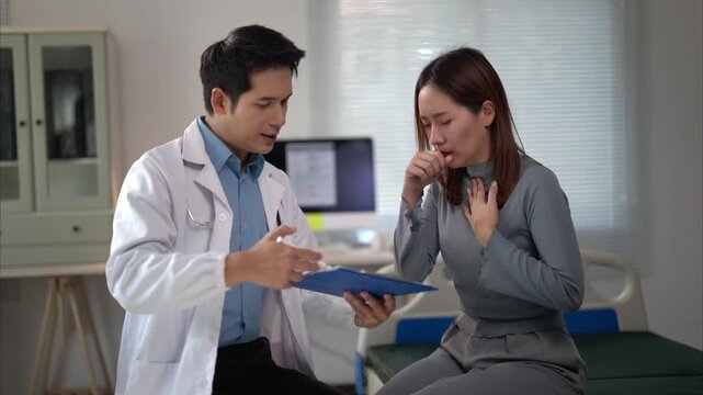 A doctor is talking to a woman in a hospital room. The woman is coughing and the doctor is trying to help her