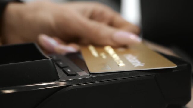 Close up hand making contactless card payment at POS terminal in retail store. Modern cashless transaction and secure banking technology indoors.