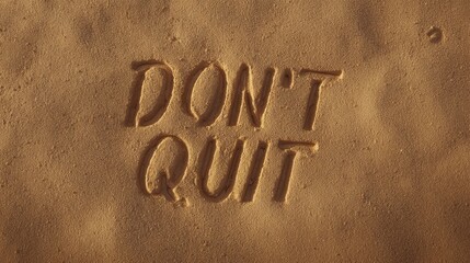 Inspirational message - Dont Quit etched in sand, a reminder of perseverance.