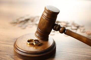 Alimony. Judge's gavel and engagement rings on wooden table, closeup