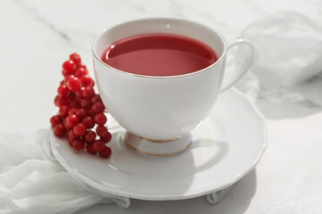 Cup of hot viburnum tea on marble background