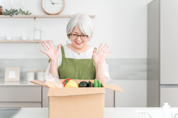 Senior/elderly woman (smiling) cooking with meal kit in her kitchen at home
