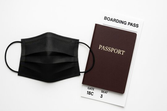 Black protective face mask with passport and boarding pass on clean white background travel safety concept for covid vacation flight health regulations airport signage and tourism campaigns