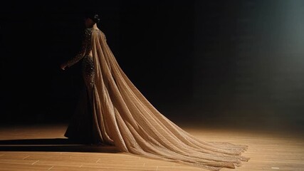 Stunning golden gown flowing dramatically as the model moves gracefully in the spotlight on the runway, creating a captivating fashion moment - Powered by Adobe