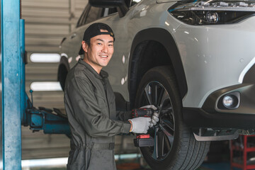 A male mechanic removing and replacing tires on a lifted car (tire change)  © buritora