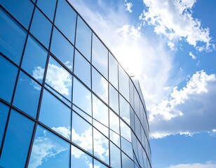 Gleaming glass facade of a modern building reflecting a bright blue sky with fluffy clouds
