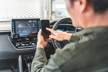 Male auto mechanic using smartphone inside a car
