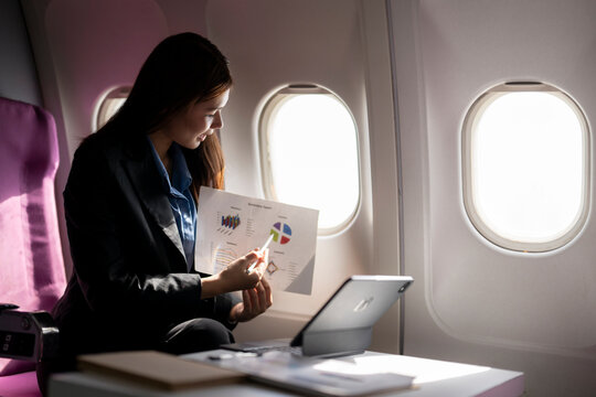 Businesswoman analyzing business report during airplane travel - Powered by Adobe