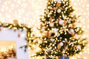 Bokeh effect from sparkling lights on Christmas tree and blurred festive garland. Holiday background for winter celebration design.