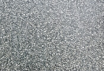 Close-up texture of grey terrazzo flooring with small stone chips, showing natural rough surface suitable for use as a background or material reference.