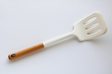 A versatile slotted spatula with a sleek white head and a wooden handle, perfect for flipping and serving, isolated on a clean white background.