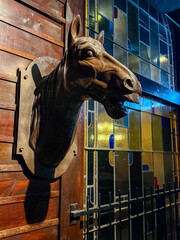 Dramatic Bronze Horse Head Wall Sculpture. Vintage Equestrian Decor Mounted on Wood Paneling Next to Colorful Stained Glass Window