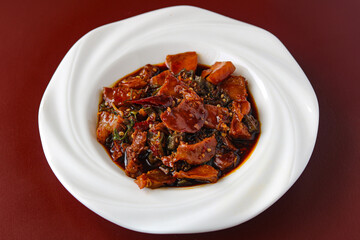 A plate of spicy pork belly, showcasing the rich, dark sauce and red chili that give the dish its bold flavor.