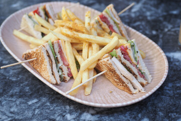 Delicious club sandwich and fries served on a plate