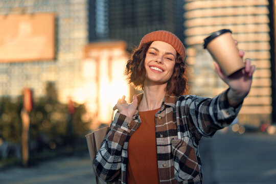 Woman smiling in city holding coffee and shopping bag at golden hour glow, candid lifestyle moment with authenticity, mindful living and emotional storytelling urban portrait.