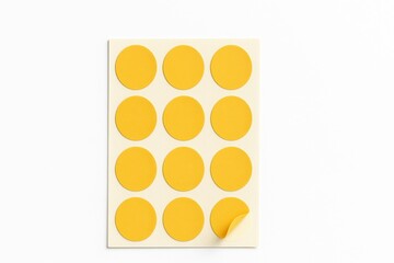 Top down studio photo of rectangular backing sheet with yellow round sticker labels neatly in rows on white background adhesive tag mockup for stationery office and planning design
