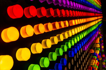 Colorful diagonal rows of glowing neon pegs forming a vibrant rainbow pattern. Bright abstract lighting and deep perspective make it ideal for tech, creative design, pride themes, and modern backgroun