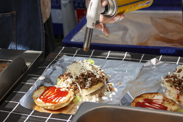 Exciting cooking food preparation using flame torch for melting cheese on delicious sandwich or...