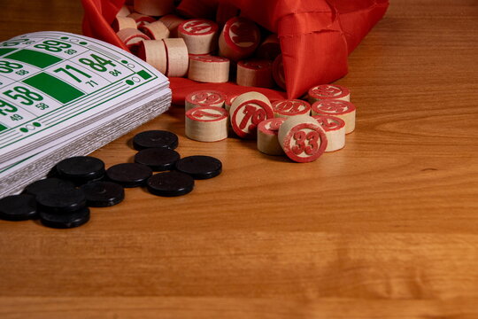 Players gathered around a wooden table enjoying a lively game of Bingo with colorful tokens and numbered cards during a fun evening at home