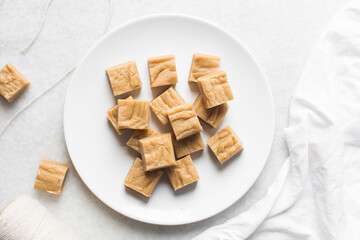 overhead view of creamy caramel fudge on a marble tray, fudge caramel candy on white background