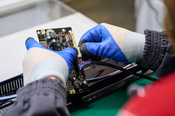 Technician assembles electronic circuit board with precision in factory environment during daytime