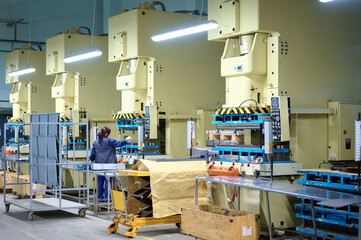Cold metal stamping and pressing production line in operation with workers and machinery at a manufacturing facility