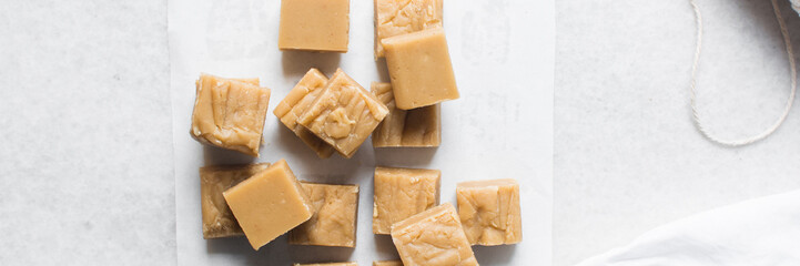 overhead view of creamy caramel fudge on a marble tray, fudge caramel candy on white background