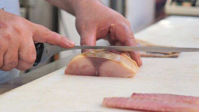 Chef skillfully Slicing Fish for Sushi.