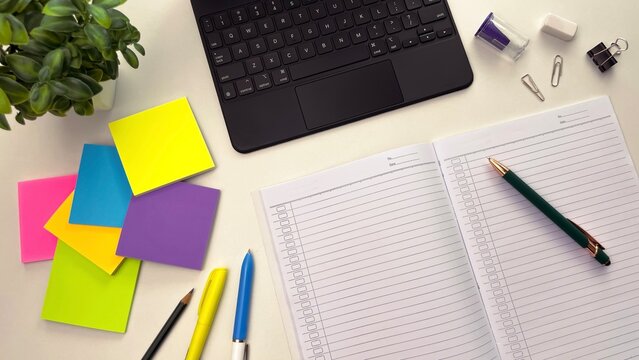 A workspace with an open planner, laptop, and colorful sticky notes. Concepts for ideation, planning, time management, and goal setting. - Powered by Adobe