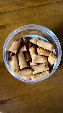 Top view of a transparent jar filled with Sumpia, a small, thin, and crispy Indonesian traditional spring roll. It's filled with dried shrimp (ebi) floss, along with seasonings.