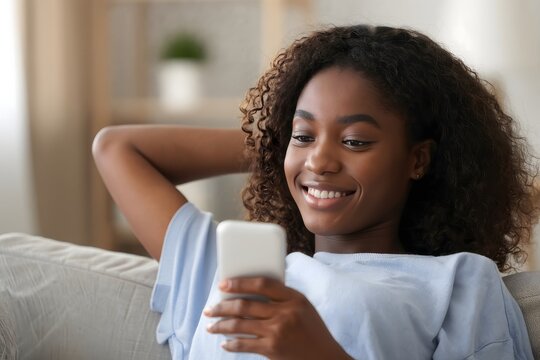 Relaxed african american woman using smartphone at home on the couch