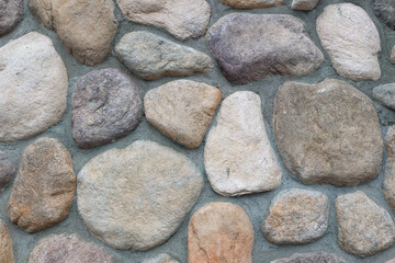 Close-up of a stone wall featuring various neutral-toned rocks arranged closely together.