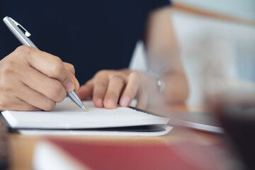 Business woman planning work project, writing on notebook with laptop computer on office table. Student studying online class and taking note on notepad, e-learning, business schedule plan