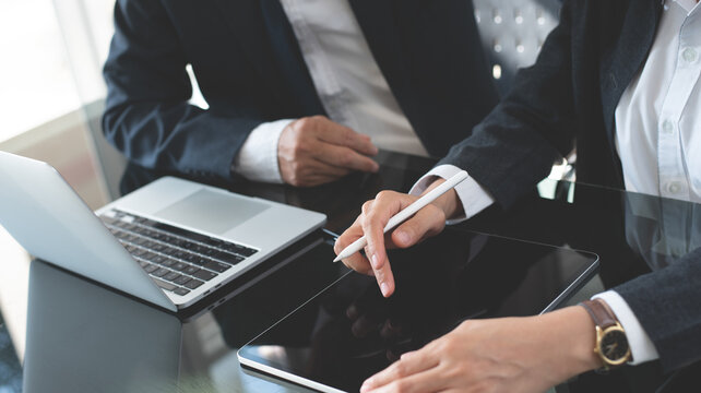 Co-working team brainstorming in modern office. Asian business colleague working on laptop computer and digital tablet, make a discussion on office table. Business teamwork