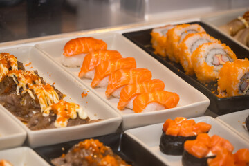 Close-up view of assorted sushi including salmon nigiri, maki rolls, and other Japanese dishes displayed in serving trays