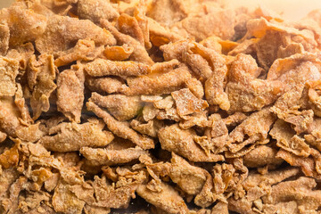 Close-up view of a pile of deep-fried crispy pork skin snacks with golden brown texture and visible seasoning