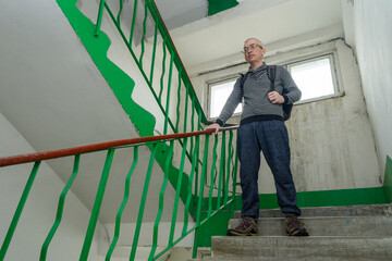man in striped sweater standing on the stairwell indoors