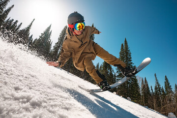 Snowboarder man jumps at big speed at forest ski slope