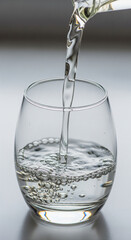 A dynamic close-up of fresh, pure drinking water being poured into a clean glass, creating bubbles and emphasizing concepts of hydration and health
