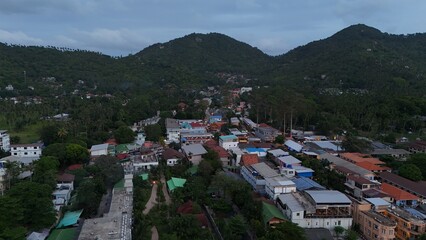 Fototapeta premium High-altitude drone shot overlooking coastal village structures and surrounding forest on Ko Tao, Thailand.