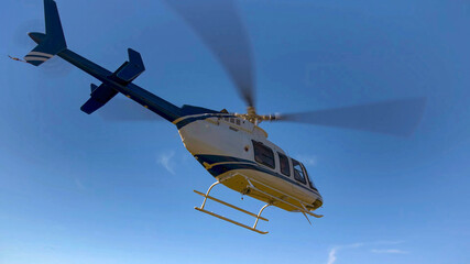 View of a flight training helicopter in the process of taking off next to natural meadows