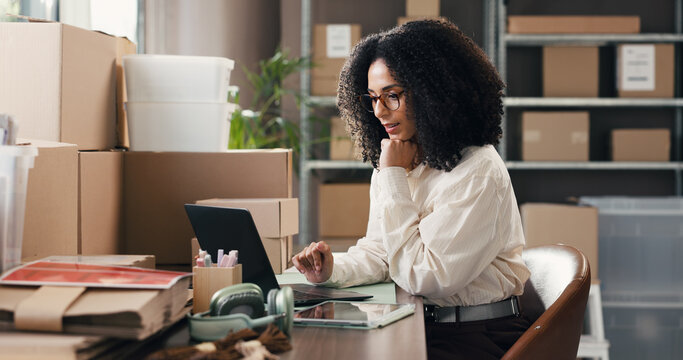Woman, laptop and thinking for dropshipping at office, supply chain and distribution schedule for boxes. Person, computer and review with package, insight or notes for inventory management at startup