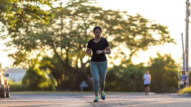 Woman morning run on city road sun light healthy community - Powered by Adobe