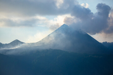 Twin Volcanic Peaks of Barren Island with Plumes of Smoke and Ash Rising Against Cloudy Morning Sky