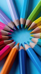 Vibrant colored pencils arranged in a circle on a light blue background, points inward, creating a central empty space