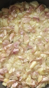Top view of crushed garlic cloves with skin deep-frying in boiling oil.