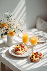 Sunlit table setting with two open-faced sandwiches topped with fruit, cream cheese, and nuts, alongside a vase of wildflowers and two glasses of orange juice